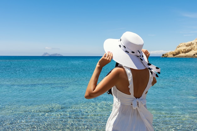 Feliz mujer con un sombrero en una playa tropical