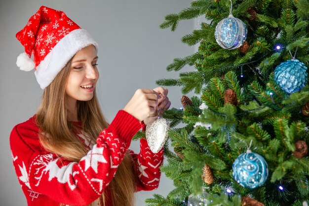 Feliz mujer con sombrero de Santa decorar árbol de Navidad