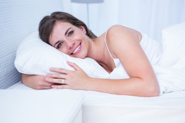 Feliz mujer sonriendo a la cámara en su cama