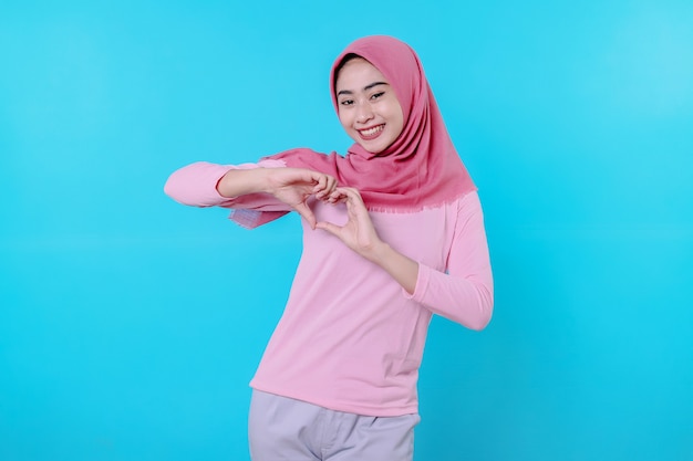 Feliz mujer sonriente con apariencia atractiva y vistiendo hijab, camiseta rosa que muestra da amor sonrisa buen humor