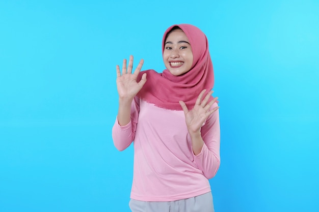 Foto feliz mujer sonriente con apariencia atractiva y vistiendo hijab, camiseta rosa que muestra diciendo hola sonrisa buen humor