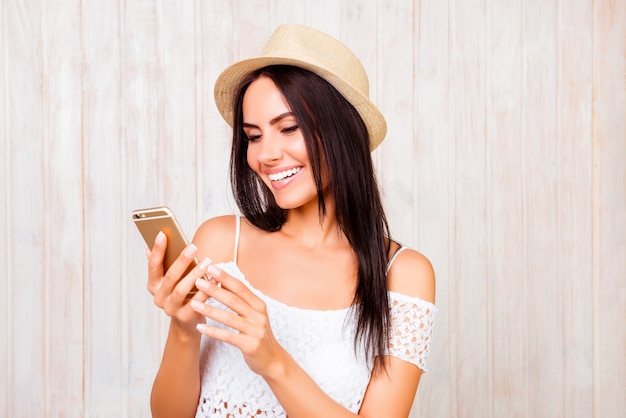 Feliz mujer sonriente con sombrero charlando por teléfono móvil