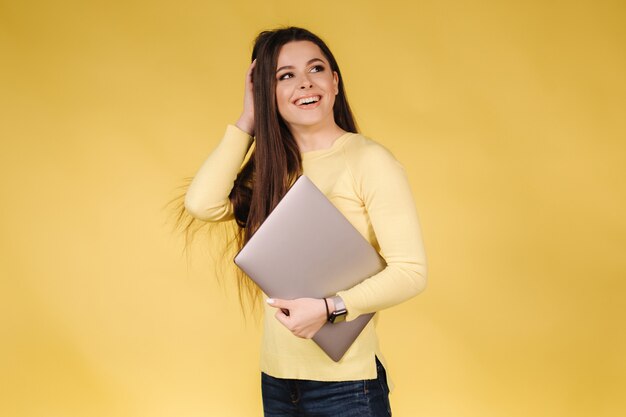 Feliz mujer sorprendida en sudadera amarilla mantenga portátil retrato de mujer bonita en amarillo