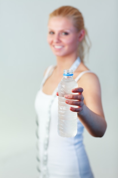 Feliz mujer sosteniendo una botella de agua con enfoque en el agua