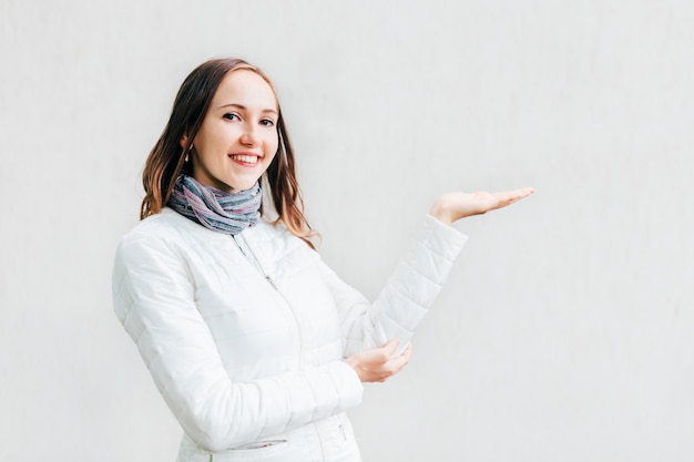 Feliz mujer sosteniendo su mano para presentar cualquier cosa y mira a la lente.