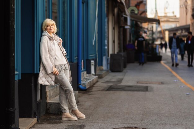 Foto feliz mulher adulta caucasiana posando na rua apoiada na parede copiar conceito de espaço de psicologia e eu