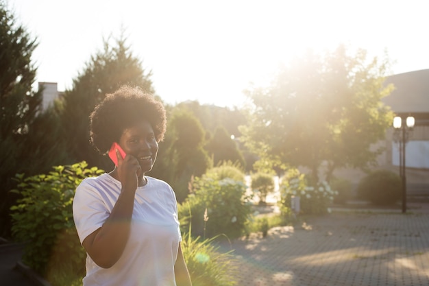 Feliz mulher afro-americana com um telefone na rua no verão.