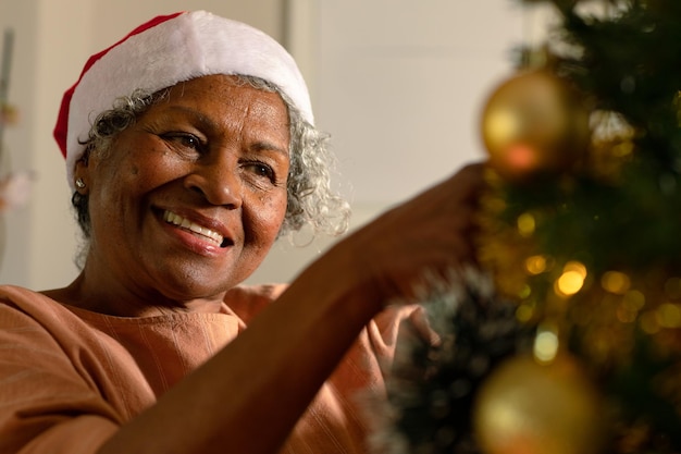 Feliz mulher afro-americana sênior decorando a árvore de natal