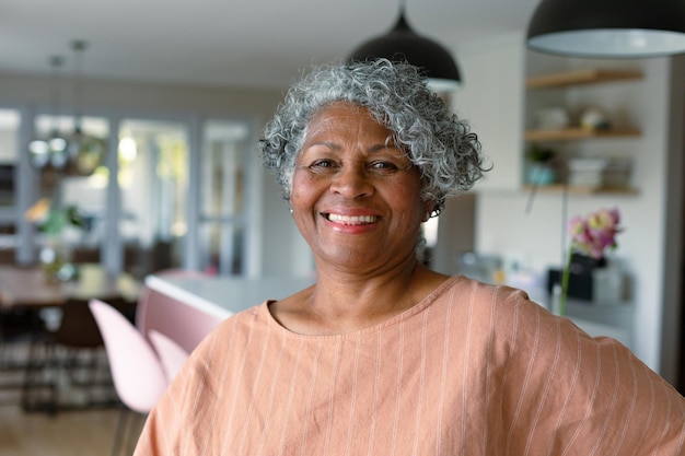 Foto feliz mulher afro-americana sênior em pé na cozinha e olhando para a câmera