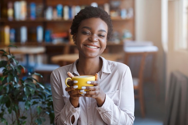 Feliz mulher afro-americana tomando café no café