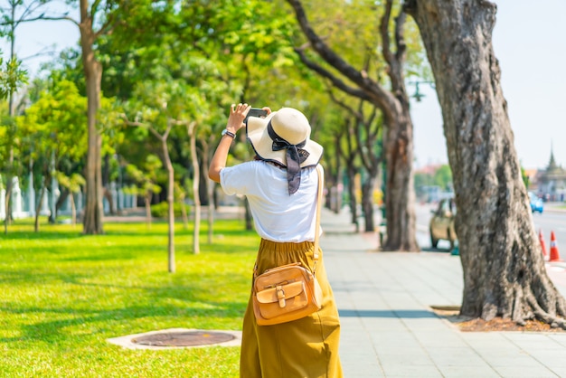 Feliz mulher asiática andando na rua e tirar fotografias