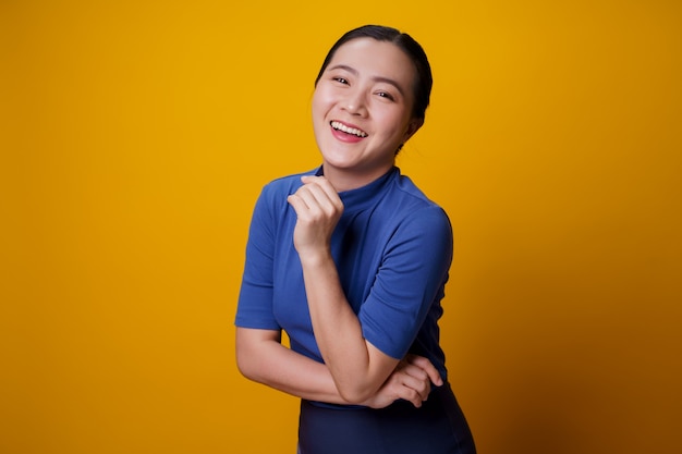 Feliz mulher asiática mostrando um sorriso dentuço em cima de amarelo.