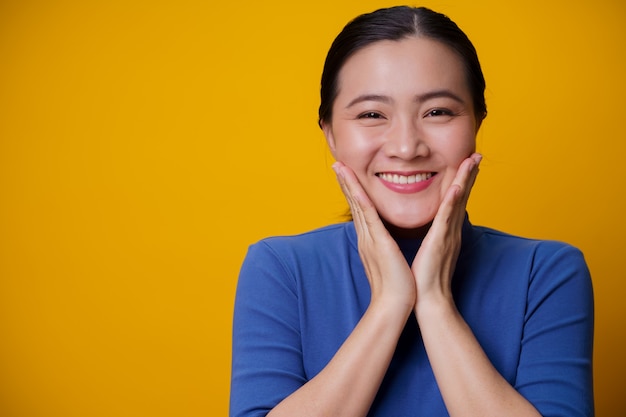 Feliz mulher asiática mostrando um sorriso dentuço em cima de amarelo.