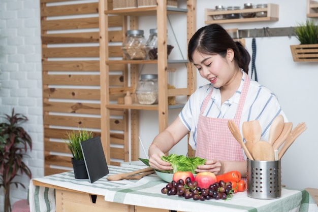 Feliz mulher asiática olhando receita tablet cozinha lendo cozinhando em casa