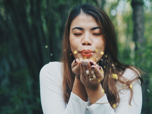 Feliz mulher asiática soprando glitter dourado.