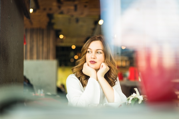 Feliz mulher bonita sentada no restaurante com dupla exposição