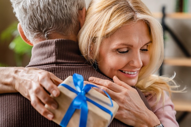 Feliz mulher de meia idade abraçando o marido grato por presente em casa