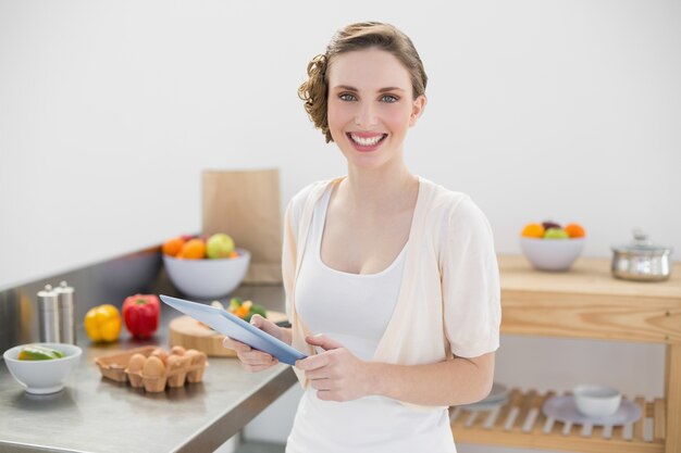 Feliz mulher deslumbrante segurando o tabuleiro em sua cozinha