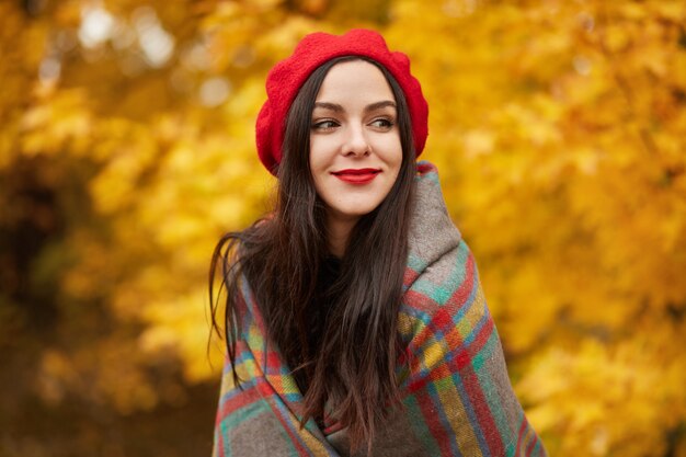 Feliz mulher despreocupada relaxante no parque outono rodeado de folhas amarelas e laranja, linda garota na floresta colorida