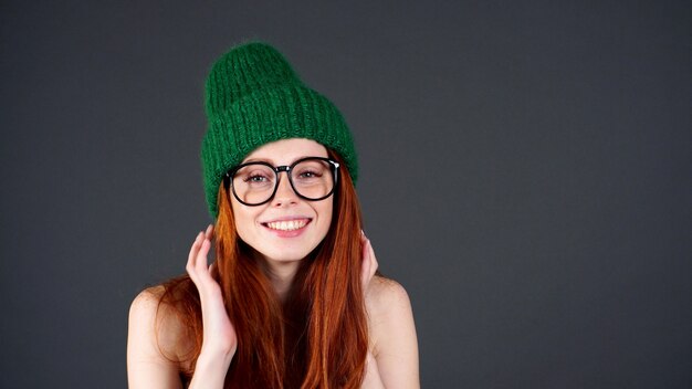 Feliz mulher jovem e bonita com cabelo comprido vermelho, dentes brancos olha para a câmera em um fundo cinza isolado