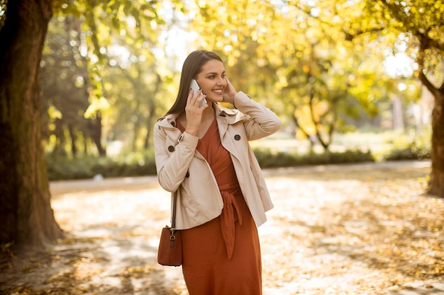 Feliz, mulher jovem, usando, telefone pilha, em, outono, parque