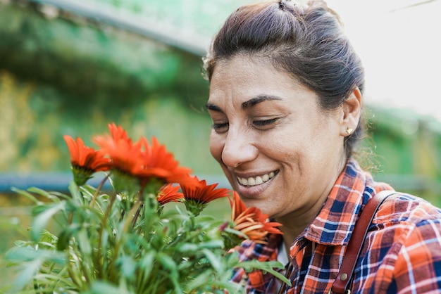 Feliz mulher latina madura trabalhando dentro do jardim com efeito de estufa