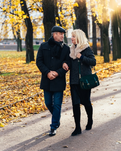 Feliz mulher madura loira e bonito homem morena de meia idade andar no parque