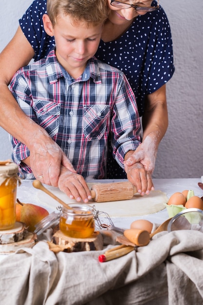 Feliz mulher madura sênior, avó e menino, neto cozinhando, amassando massa, assando torta, bolo, biscoitos. tempo para a família na cozinha aconchegante. atividade de outono em casa.