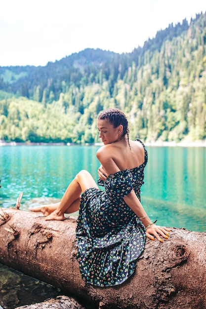 Feliz mulher romântica sentada à beira do lago espirrando água