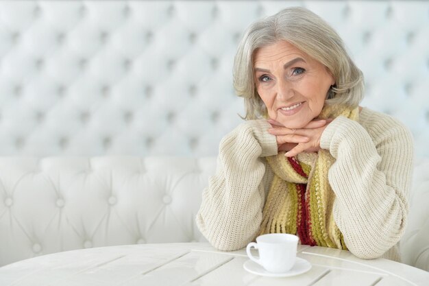 feliz mulher sênior à mesa com uma xícara de chá