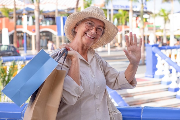 Foto feliz mulher sênior lucra com a venda de verão para fazer compras senhora bonita idosa carregando sacolas de compras olhando para a câmera sorrindo