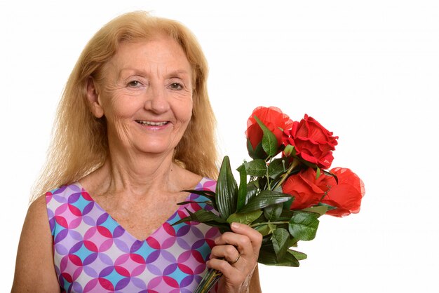 feliz mulher sênior sorrindo e segurando rosas vermelhas