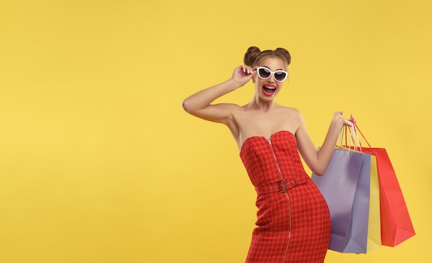 Feliz mulher vestindo vermelho dos ombros vestido segurando sacolas de compras