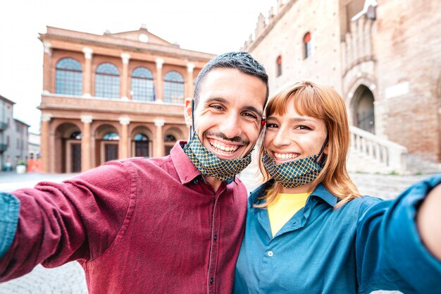 Feliz namorado e namorada apaixonada tomando selfie com máscaras no tour pela cidade velha