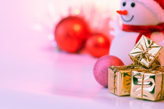 Feliz Natal, ano novo, boneco de neve, presentes em caixas de ouro e bolas vermelhas em um rosa.