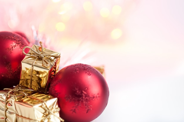 Feliz Natal, Ano Novo, presentes em caixas de ouro, bolas de Natal vermelhas são empilhadas no canto esquerdo. Bokeh de fundo.