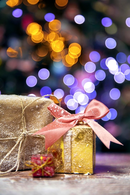 Feliz natal, ano novo, presentes em caixas de ouro com laço rosa na neve, bokeh fundo da árvore de natal com espaço de cópia, férias, espaço de conceito presente para texto