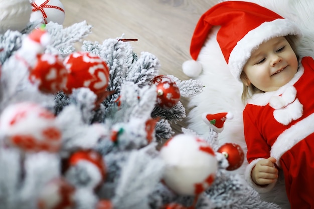 Feliz Natal brilhante. Bebê adorável, aproveite o Natal. Memórias de infância. Santa menina criança comemorar o Natal em casa. Feriado familiar. Menina bonita criança alegre humor brincar perto de árvore de Natal.