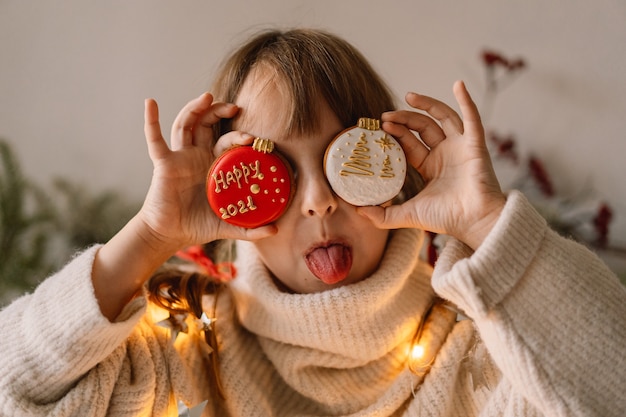 Feliz Natal e Boas Festas. A criança brinca com biscoitos de gengibre. A espera do Natal.