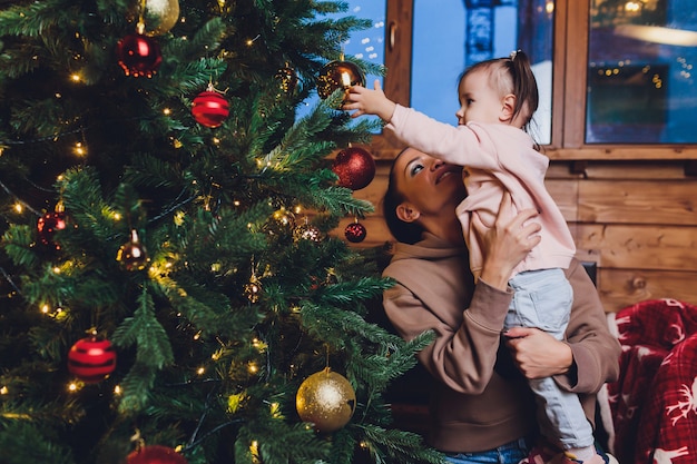 Feliz Natal e boas festas Mãe alegre e sua filha filha trocar presentes. Pai e filho se divertindo perto de árvore de Natal dentro de casa. Família amorosa com presentes no quarto.