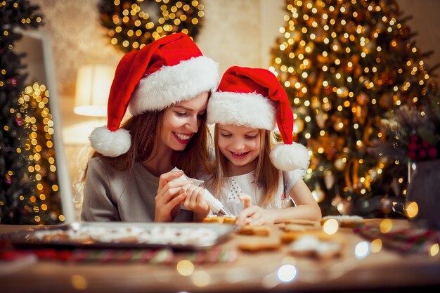 Feliz Natal e boas festas. Mãe e filha cozinhando biscoitos de Natal.