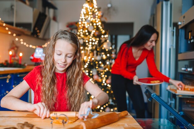 Feliz natal e boas festas. mãe e filhas cozinhando biscoitos de natal