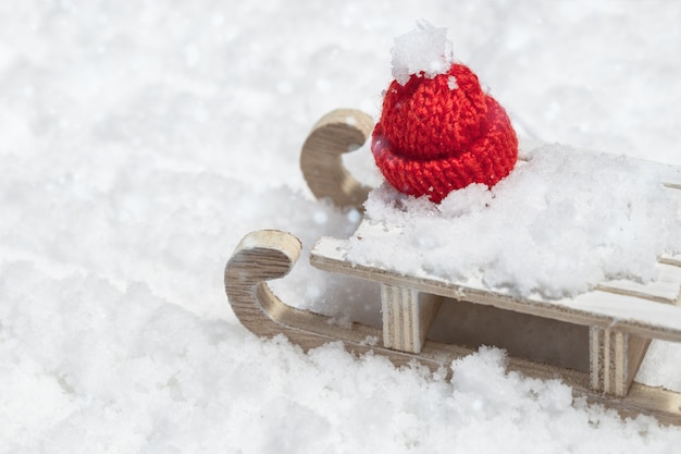 Feliz Natal e feliz ano novo cartão com trenó de madeira e boné vermelho de Natal em fundo de neve com espaço de cópia. Foco seletivo.