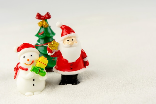 Feliz Natal e feliz ano novo conceito. Papai Noel fofo, boneco de neve e árvore na neve com espaço de cópia