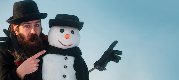 Foto feliz natal e feliz ano novo, engraçado homem de neve de inverno com chapéu brincando com boneco de neve ao ar livre