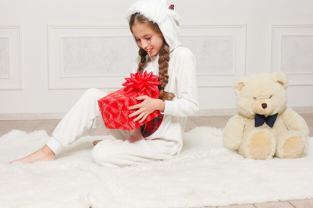 Feliz Natal e Feliz Ano Novo Linda criança feliz menina de pijama esperando um milagre em casa com árvore de Natal