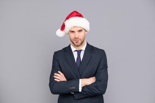 Feliz Natal. empresário de terno e chapéu de Papai Noel. festa corporativa de natal. homem de negócios confiante em fundo cinza. feliz Ano Novo.