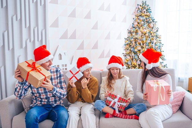 Feliz Natal. Família de quatro pessoas com presentes de Natal em casa