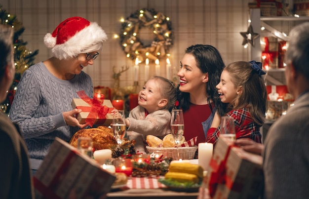 Feliz natal. família feliz está jantando em casa. férias de celebração e união perto da árvore.