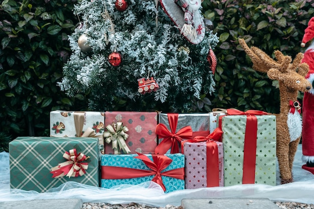 Feliz Natal Fechamento de várias caixas de presente Bolas coloridas e pacote de fotos de saudação de Natal Decoração de boneca de Papai Noel no fundo verde da árvore de Natal Decoração durante o Natal e o Ano Novo